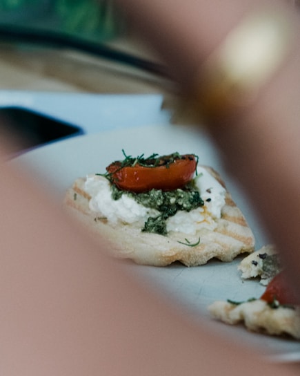Close-up of a sizzling hot tapa with melted cheese and fresh herbs on a rustic wooden board.