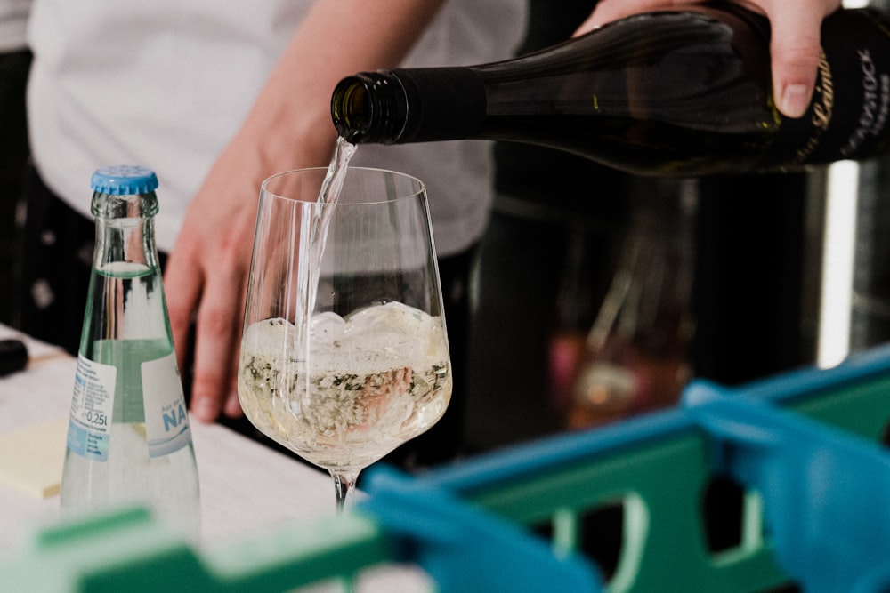 a person pouring a glass of wine into a wine glass