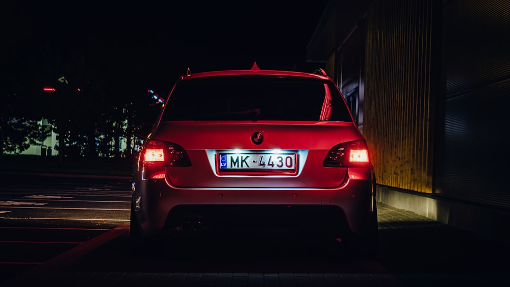 um carro vermelho estacionado em um estacionamento à noite