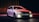 A sleek and modern BMW station wagon is parked under dramatic lighting. The car's headlights are on, creating a powerful contrast against the dark background. The reflective surface of the vehicle captures red and blue lighting accents, emphasizing its aerodynamic design.