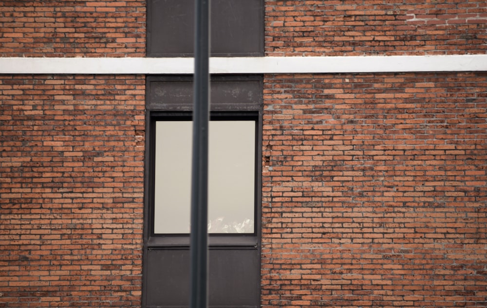 a brick building with a window and a street sign in front of it