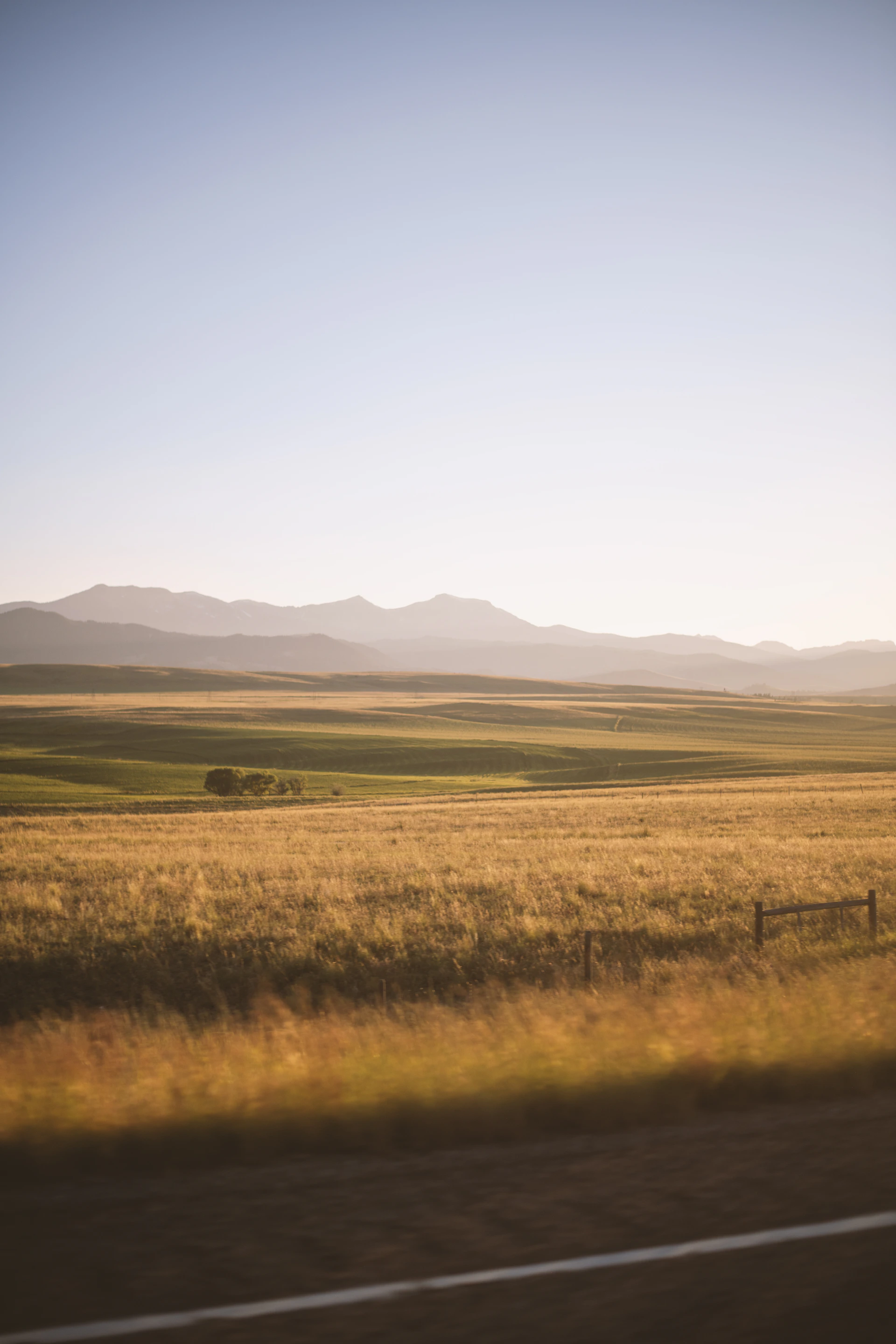 a field with a fence and mountains in the background