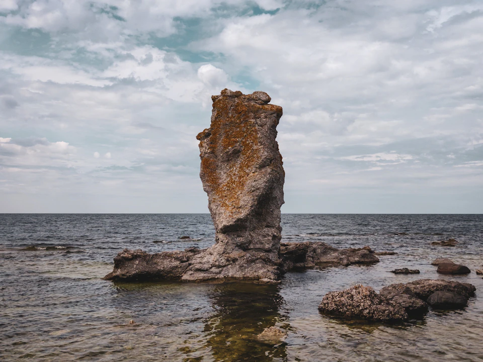 Rocky outcropping jutting into the ocean with lichen-covered boulder and scattered smaller rocks nearby