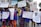 A group of children and adults are holding up various signs advocating for disability rights and inclusion in sports. The signs have messages like 'We want unified sports in the Paralympics to mainstream disability,' 'Support disability rights,' 'Don't look at the less, look at the records,' and 'Yes I can.' The participants are wearing blue shirts with orange and red lettering and are standing on an outdoor street with trees and buildings in the background.