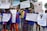 A group of children and adults are holding up various signs advocating for disability rights and inclusion in sports. The signs have messages like 'We want unified sports in the Paralympics to mainstream disability,' 'Support disability rights,' 'Don't look at the less, look at the records,' and 'Yes I can.' The participants are wearing blue shirts with orange and red lettering and are standing on an outdoor street with trees and buildings in the background.