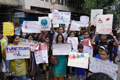 A group of people is gathered holding various signs and posters advocating for disability rights and empowerment. The signs carry messages promoting inclusivity, equal opportunities, and changing perceptions about disabilities. The crowd consists of diverse individuals, including children and adults.