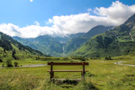 A peaceful wooden bench overlooking misty mountains under a clear blue sky.
