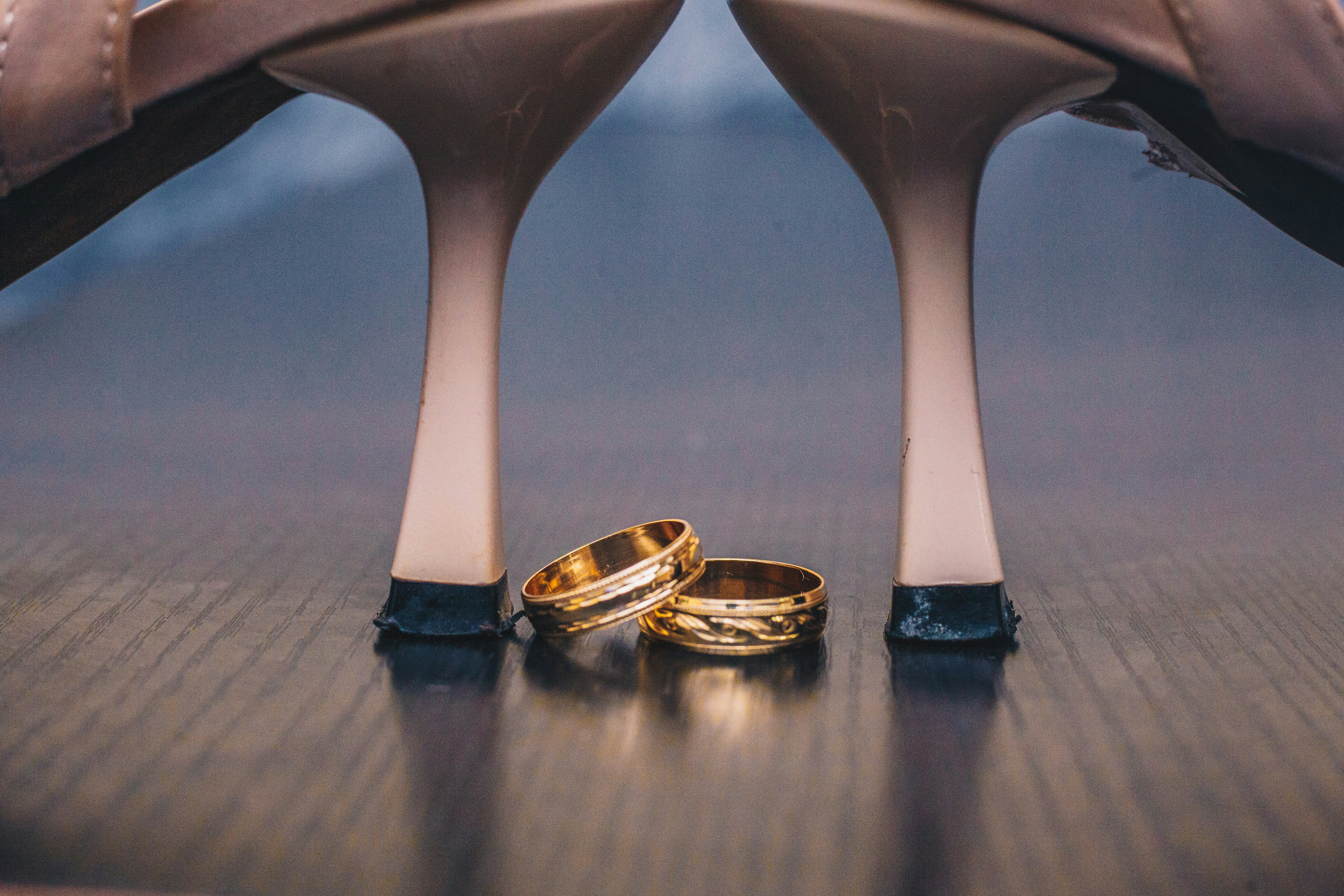 a pair of gold wedding rings sitting on top of a wooden table