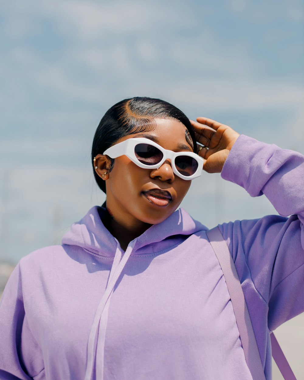 a woman in a purple sweatshirt and white sunglasses