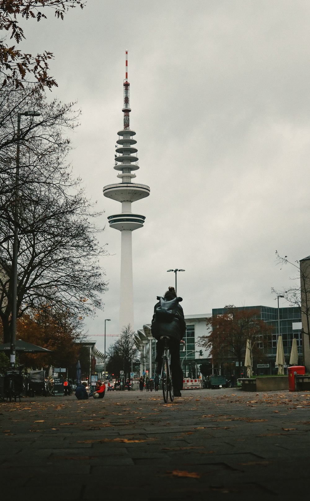 a man riding a bike down a street next to a tall tower