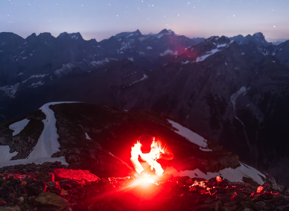 a person sitting on top of a mountain next to a fire