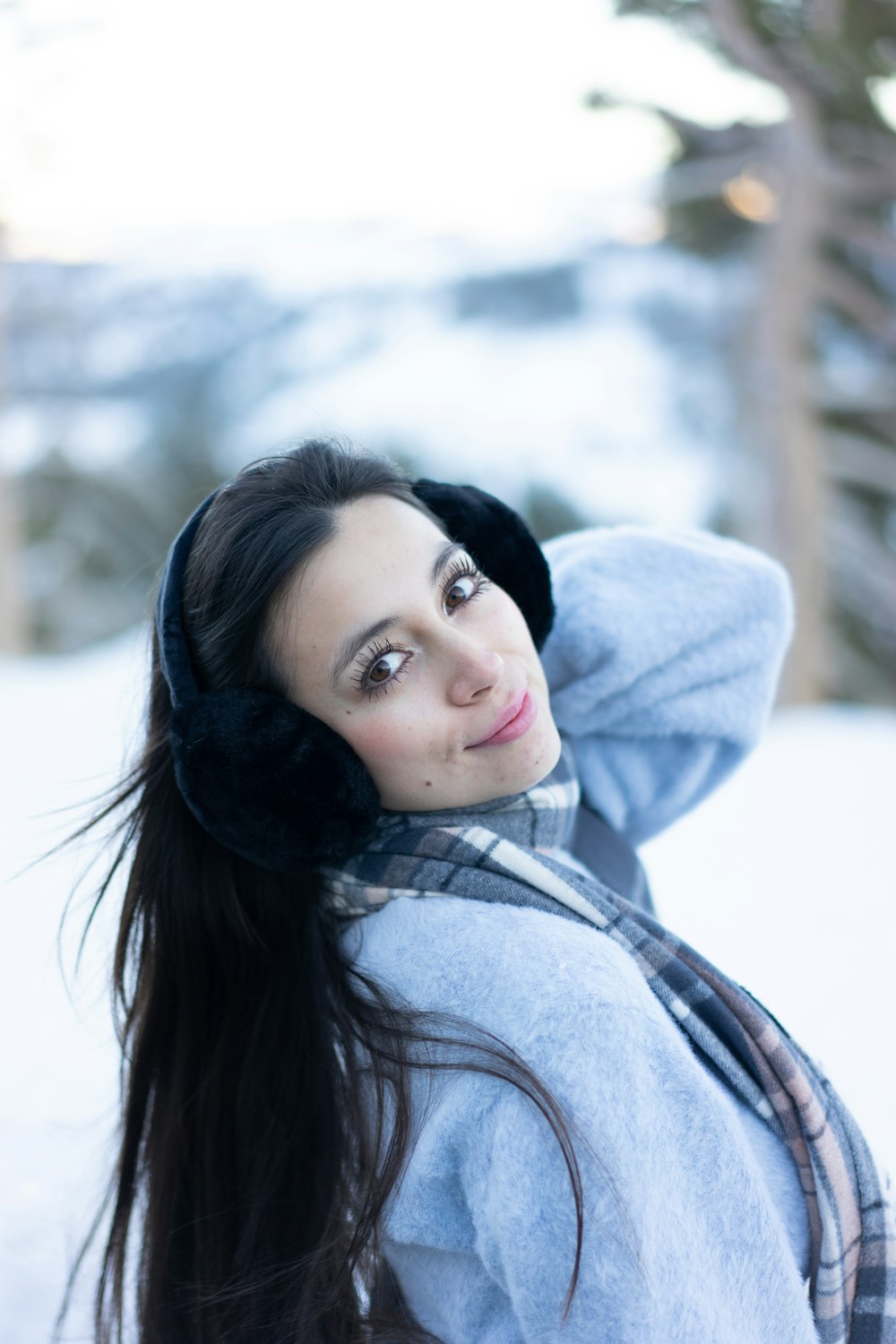 a woman with long hair wearing a scarf and ear muffs