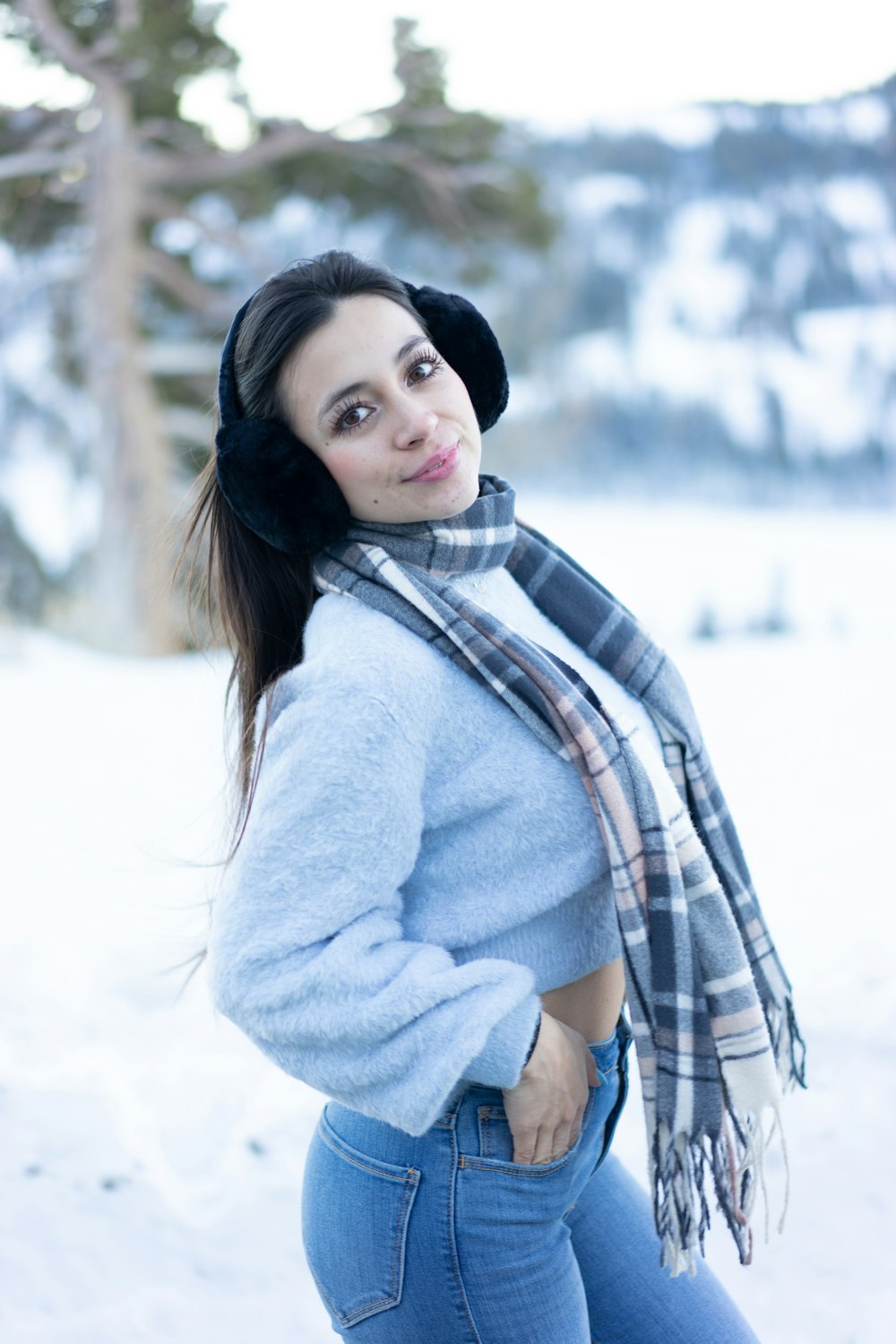 a woman standing in the snow wearing a scarf