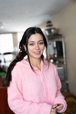 A friendly customer service representative smiling, with a soft pink and white background.