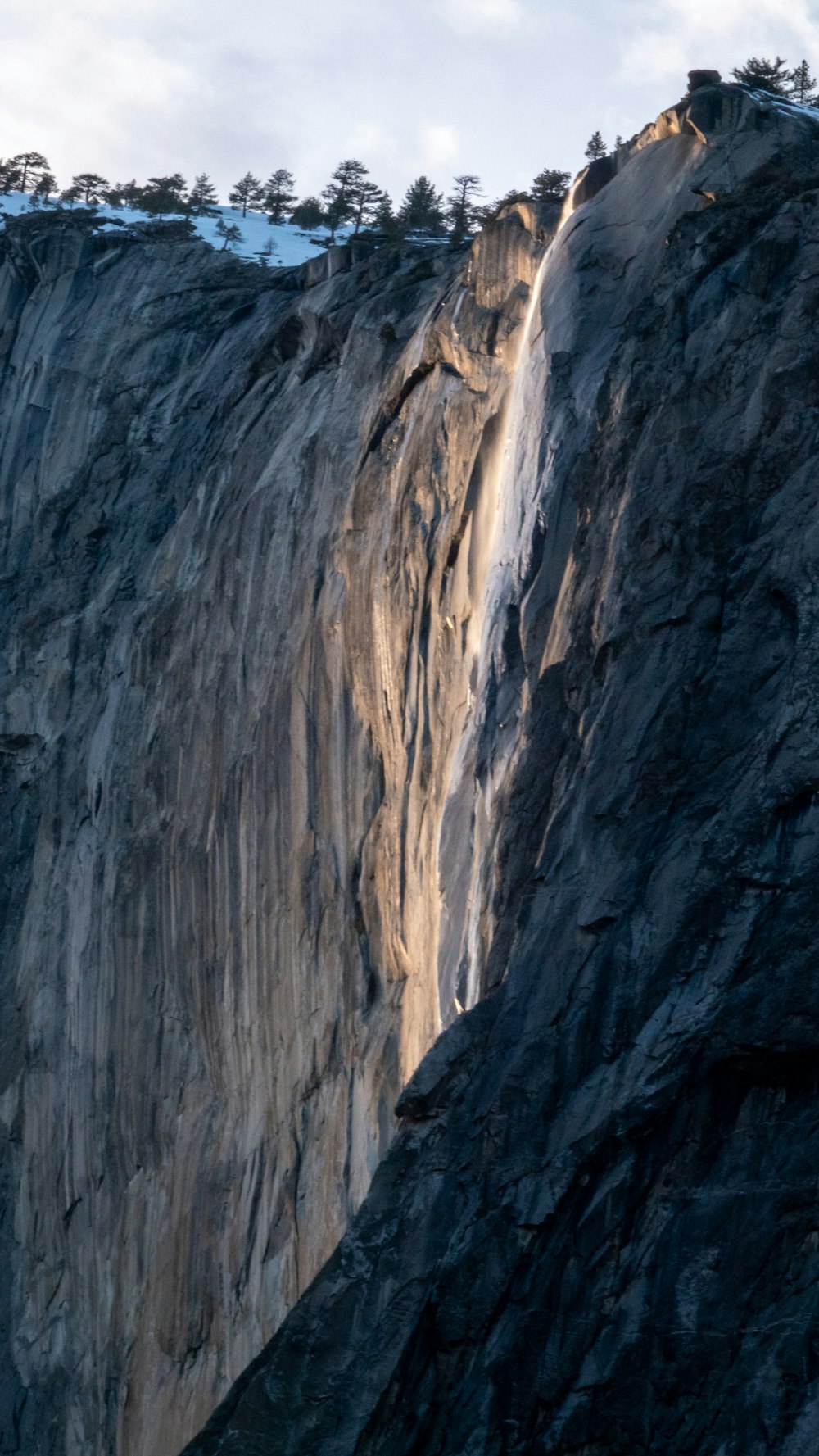 a mountain side with a very tall waterfall