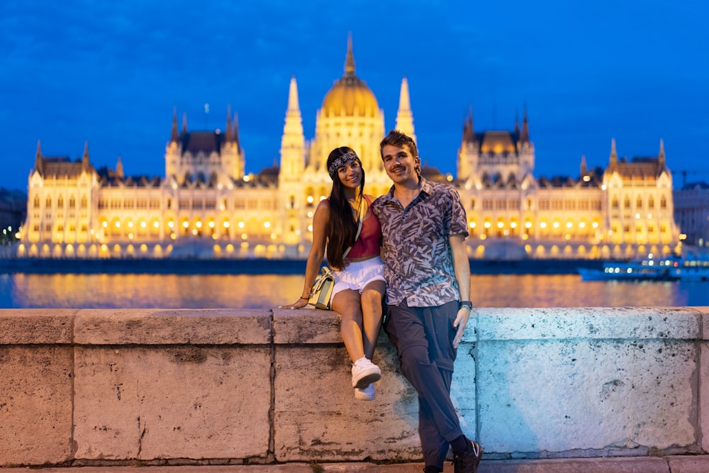 a man and a woman posing for a picture in front of a castle
