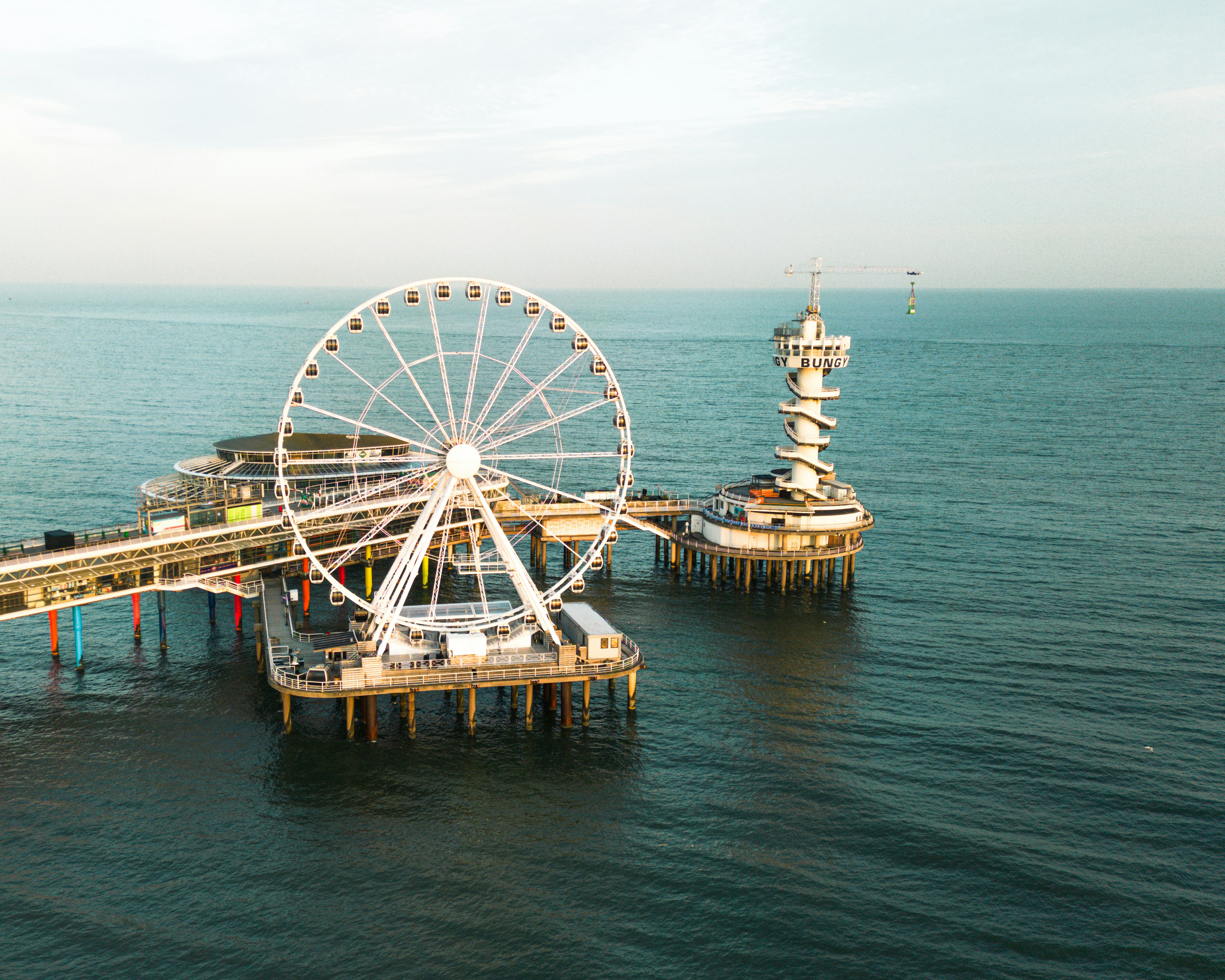 a ferris wheel sitting on top of a pier next to the ocean