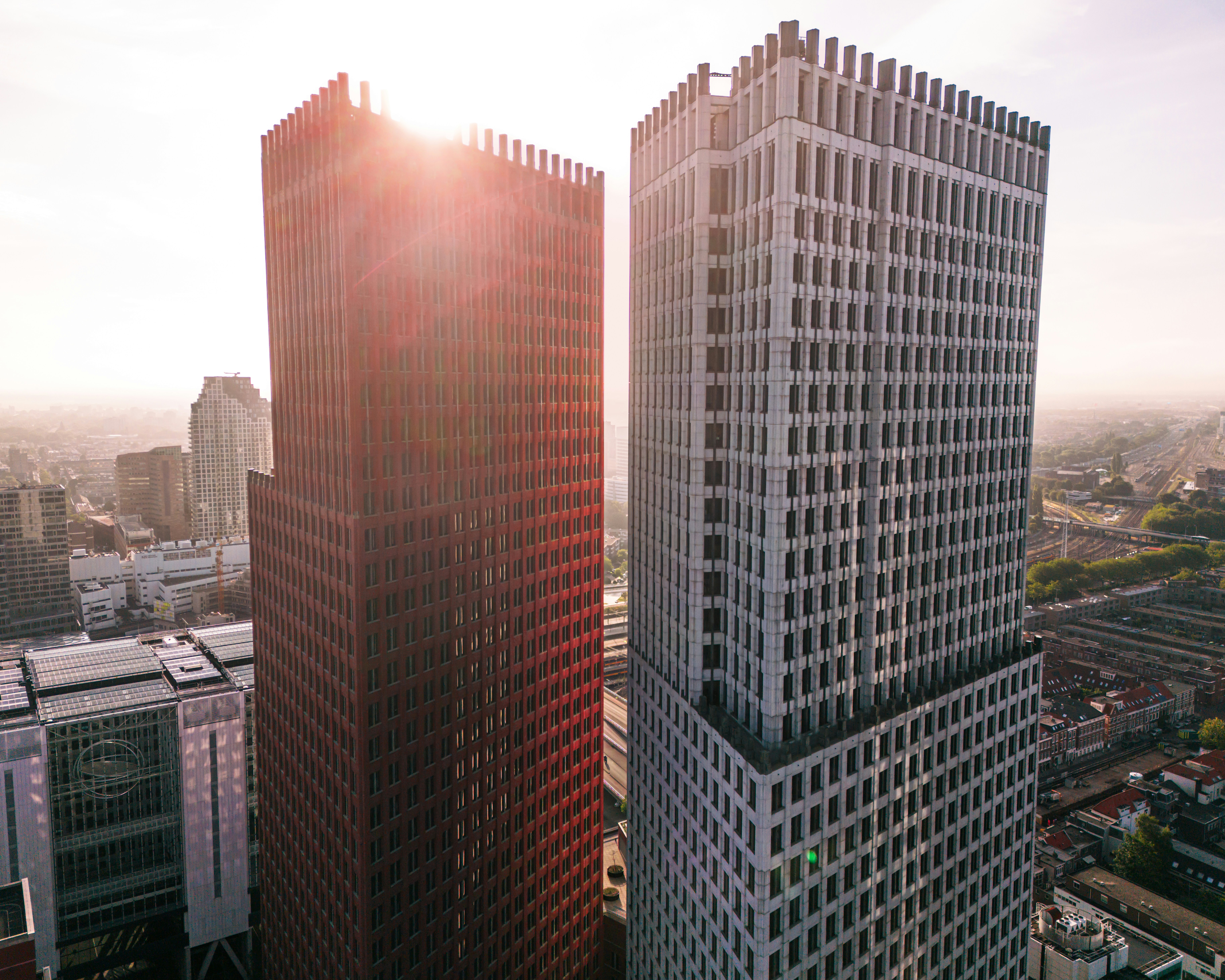 two tall buildings in a city with the sun shining through the windows