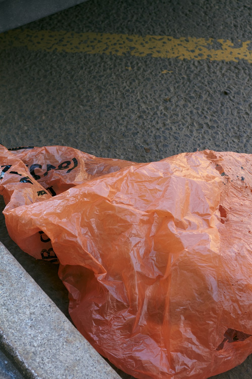 an orange plastic bag sitting on the side of a road