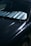 A close-up view of a car windshield with a reflective sunshade in place to block sunlight. The surface of the car is visible with reflections and subtle scratches on a dark paint.