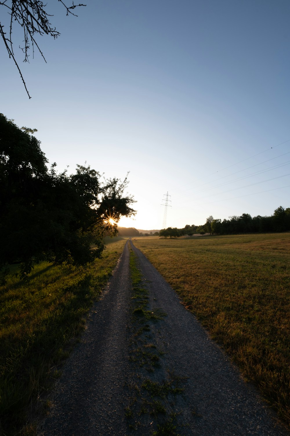 the sun is setting on a dirt road