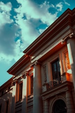 A stately stone building with classical columns bathed in warm morning light.