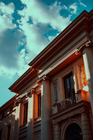 A stately stone building with classical columns bathed in warm morning light.