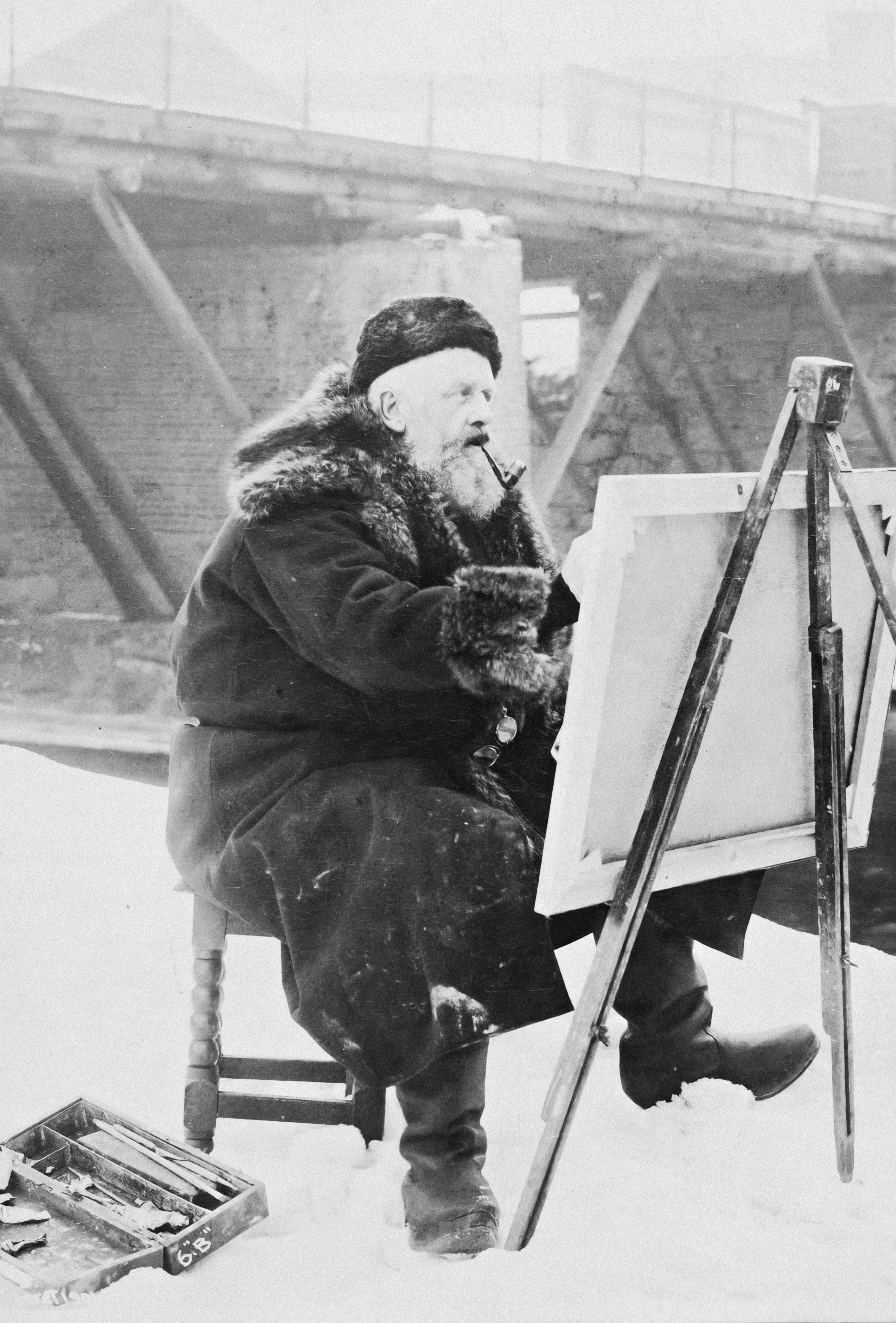 a man sitting in front of a easel painting a picture