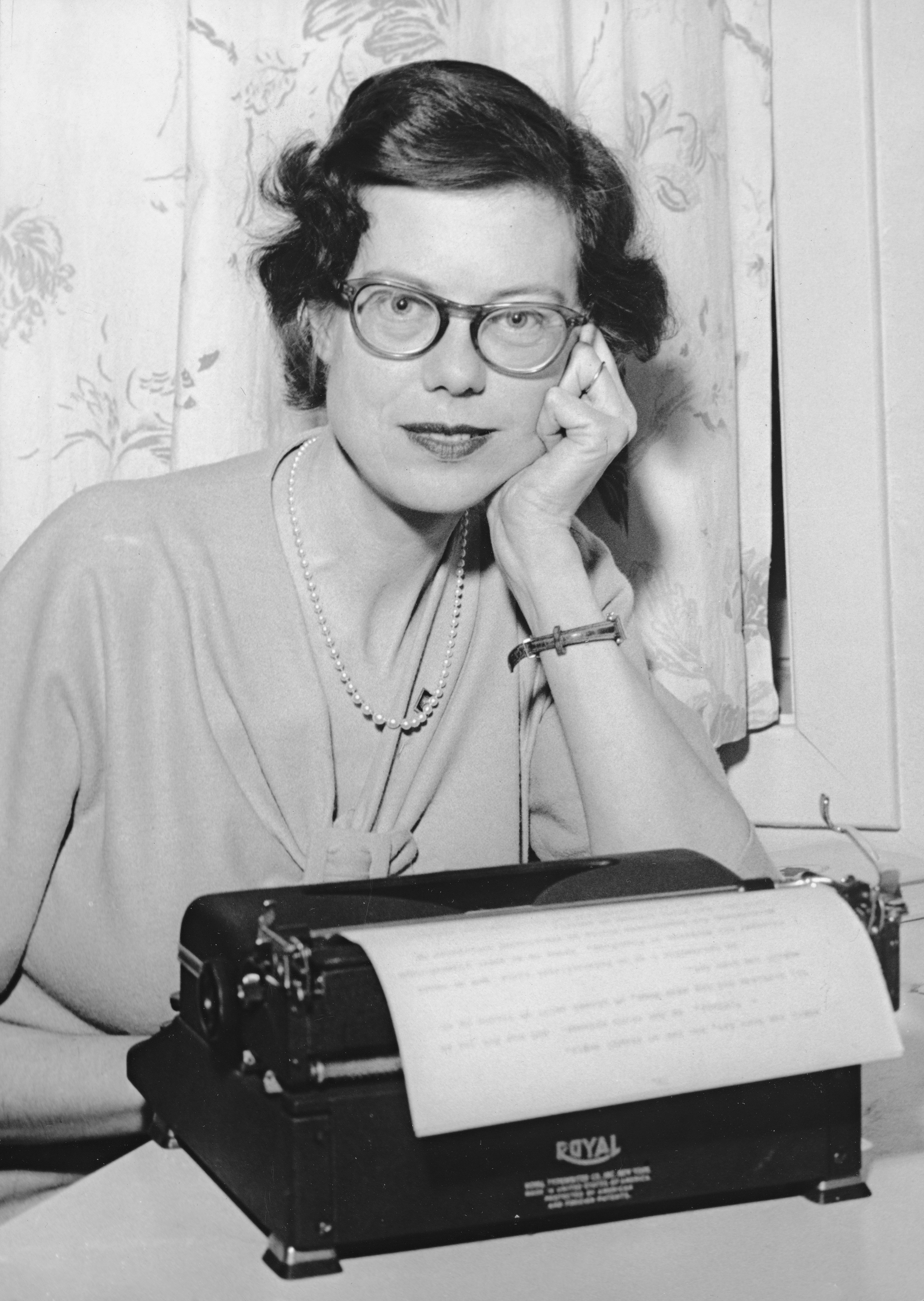 a woman sitting at a desk with a typewriter