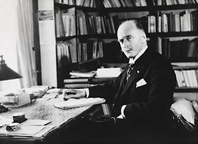 Casual photo of a man working thoughtfully at his desk with books around