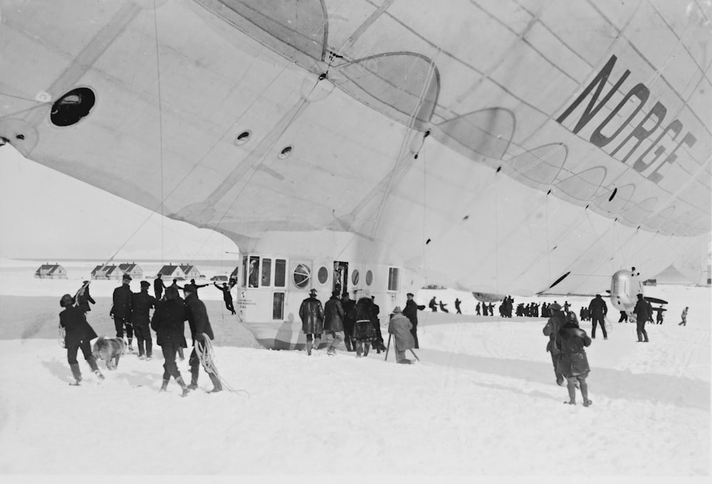 a group of people standing around an airplane in the snow