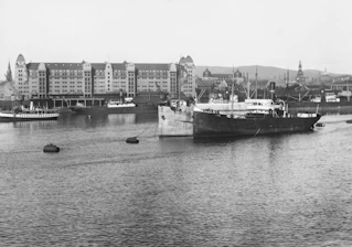 Historic black and white photo of Passage West harbor with old sailing ships docked.