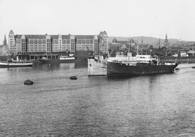 Historic black and white photo of Passage West harbor with old sailing ships docked.
