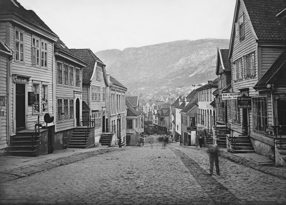 a black and white photo of a person walking down a cobblestone street