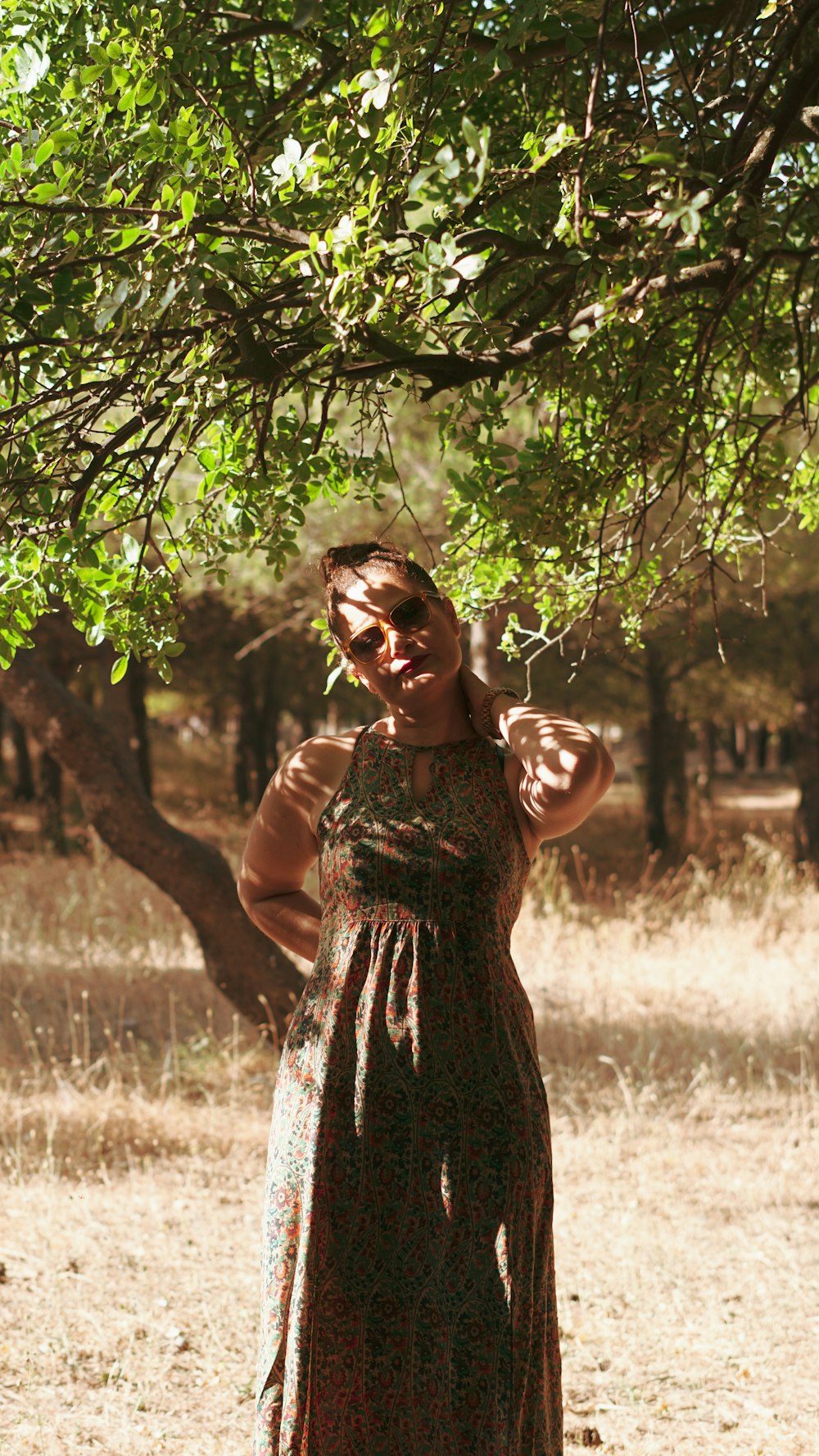 a woman in a dress standing under a tree