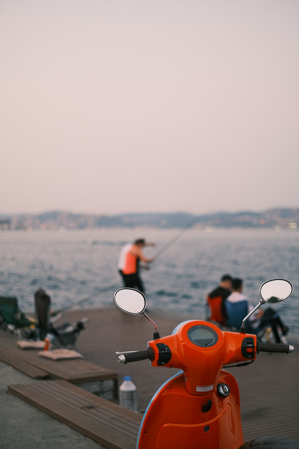 a scooter is parked on a pier near the water