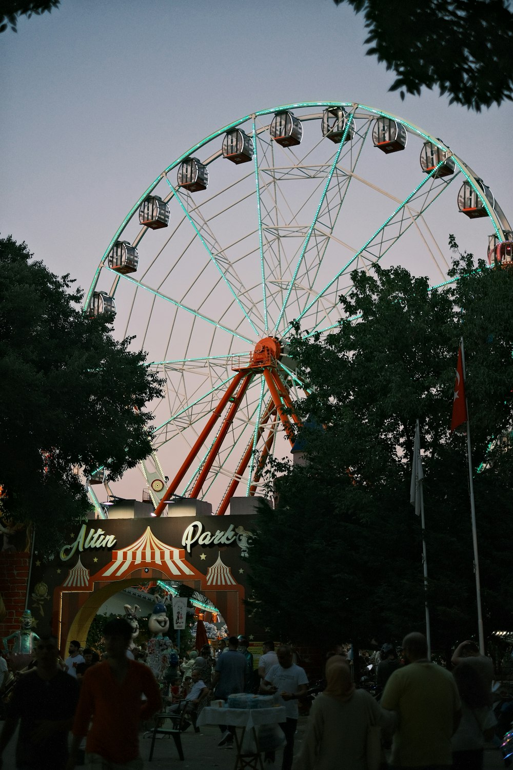a ferris wheel in a park with people walking around