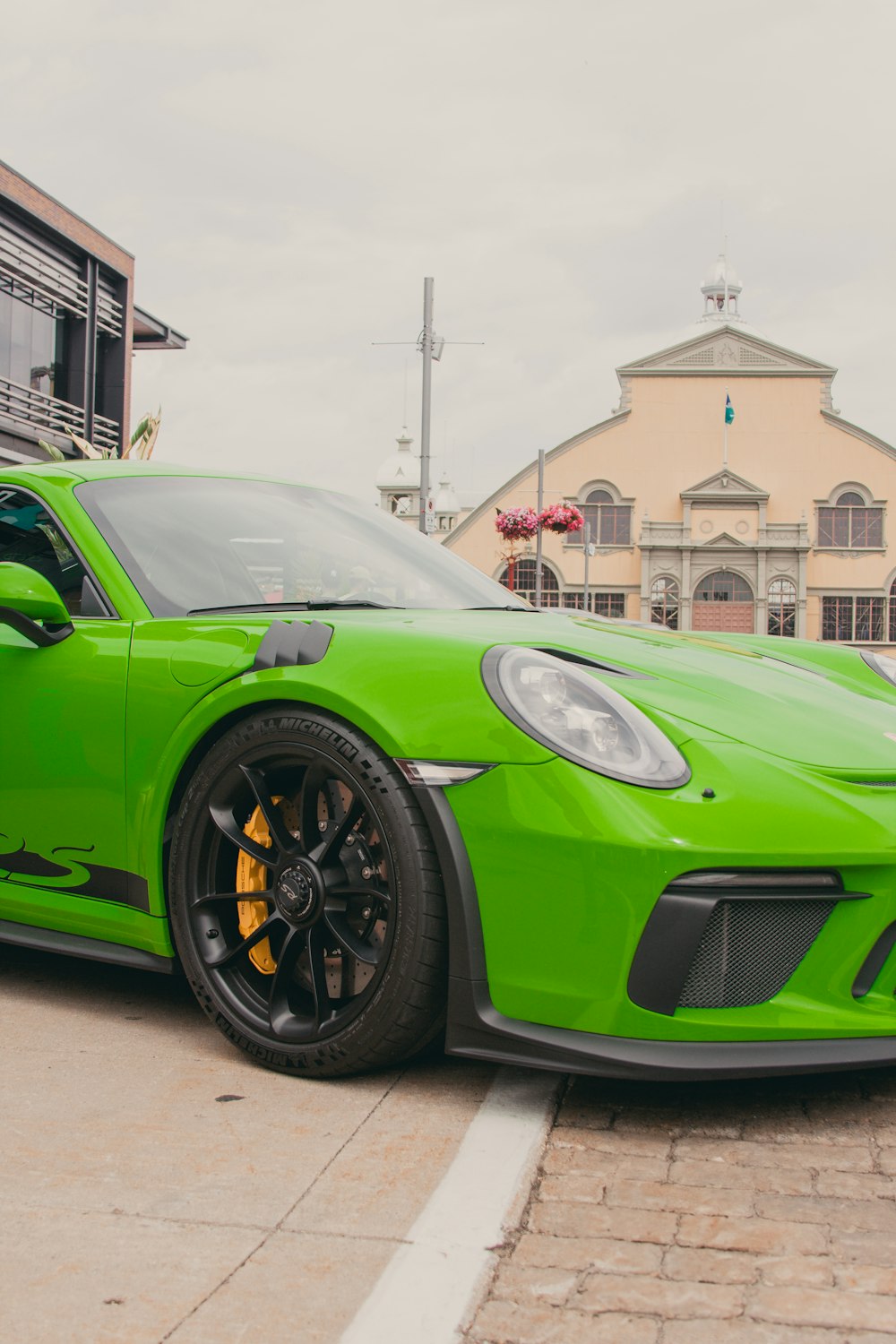 a green sports car parked in front of a building