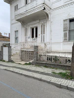 Craftsman carefully restoring ornate trim on a historic home's porch.