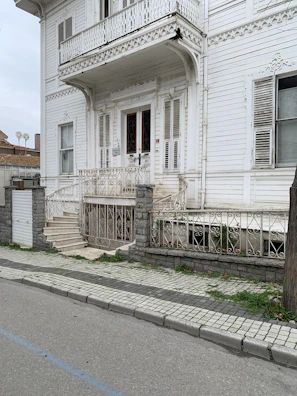 Craftsman carefully restoring ornate trim on a historic home's porch.
