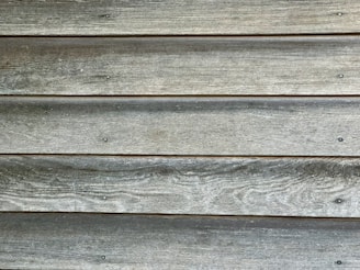Weathered wooden planks aligned horizontally with visible grain texture and evenly spaced nails.