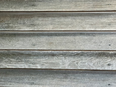 Weathered wooden planks aligned horizontally with visible grain texture and evenly spaced nails.