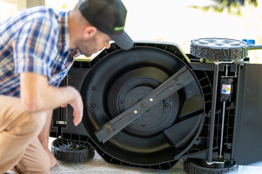 Technician performing a detailed tune-up on a lawn mower engine outdoors.