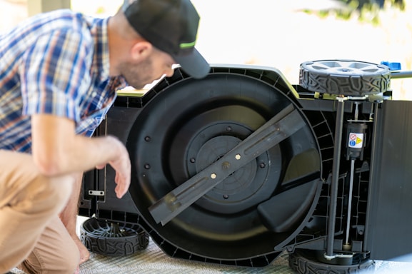 A friendly technician from Flying Wrench Mobile Repairs working on a lawn mower in a customer's driveway.