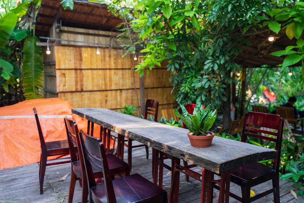 a wooden table with chairs and a potted plant on top of it