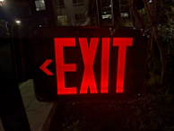 Night view of a building with illuminated emergency exit signs and sprinkler heads.