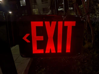 Night view of a building with illuminated emergency exit signs and sprinkler heads.