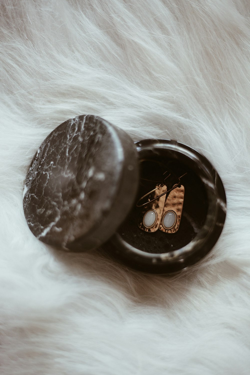 a pair of earrings sitting on top of a white fur