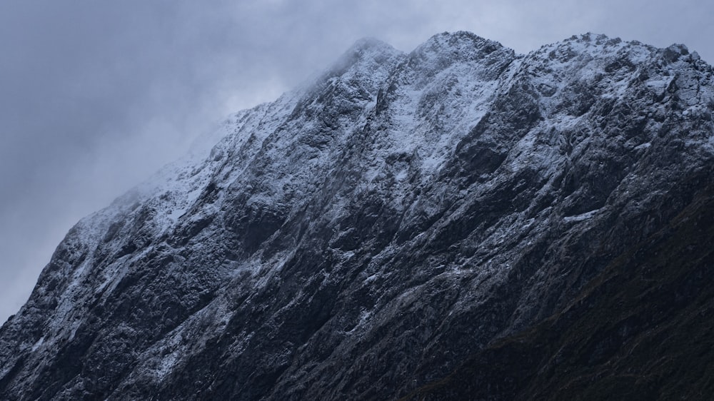 a very tall mountain covered in snow under a cloudy sky
