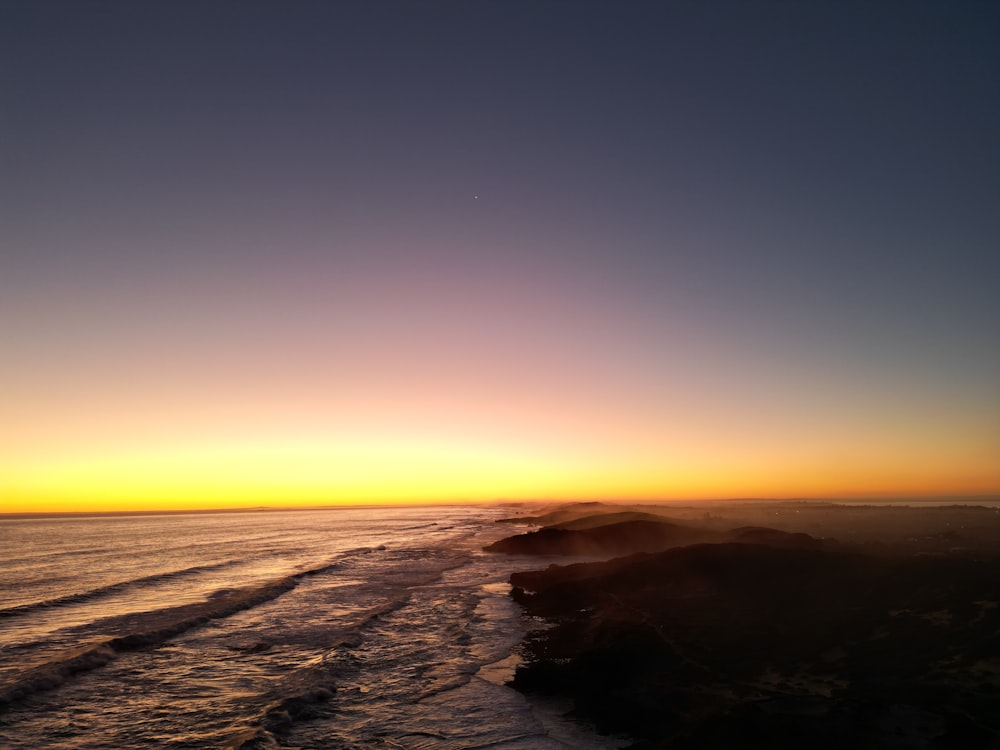 the sun is setting over the ocean with waves